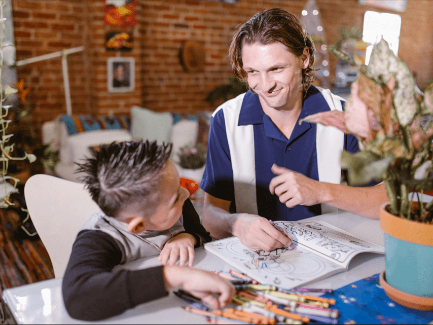 Opiekun wspiera chłopca przy kolorowaniu